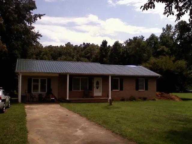 Dark green metal roof on a brick ranch with a covered porch in Union City